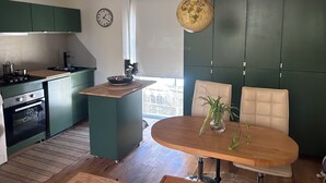 Eine moderne Küche mit grünen Schränken, einem Holzes Esstisch und einem Globus, der von der Decke hängt.