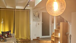 Ein modernes Wohnzimmer mit einer Couch, einer großen Hängeleuchte, Holzböden und einer Treppe zu einer oberen Ebene.
