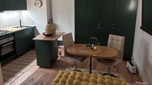 Eine kleine Küche mit Essbereich, einer Wanduhr und einem grünen Schrank.