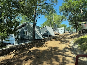 A residential area with houses on a hillside, a dirt path, and a construction vehicle. - Cozy 840 sq ft A-frame cabin at North Shore Resort with lake views, 1 bedroom + loft (sleeps 6), full kitchen, island seating, and a private deck—perfect for relaxing getaways at Lake of the Ozarks. (Eldon)