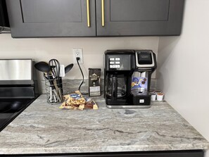 A kitchen with a coffee maker, a bag of coffee pods, and a coffee grinder. - Cozy 840 sq ft A-frame cabin at North Shore Resort with lake views, 1 bedroom + loft (sleeps 6), full kitchen, island seating, and a private deck—perfect for relaxing getaways at Lake of the Ozarks. (Eldon)