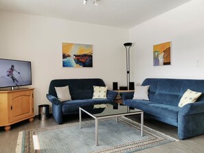 A living room with two sofas, a coffee table, a TV, and artwork on the walls. - Gitzifurka 4 # 4-bed apartment, Dusche, WC 4-Bettwohnung, Dusche, WC by Interhome (Leukerbad)