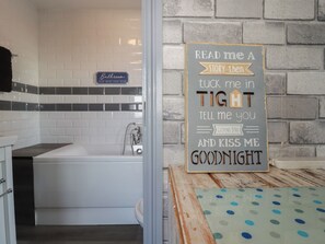 A bathroom with a sign indicating it's the bathroom, a bathtub, and a sign on the wall with a message. - Shoreline Apartment No.3 (Newquay)