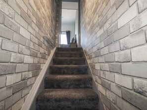 A staircase with carpeted steps leading to a door at the top. - Shoreline Apartment No.3 (Newquay)
