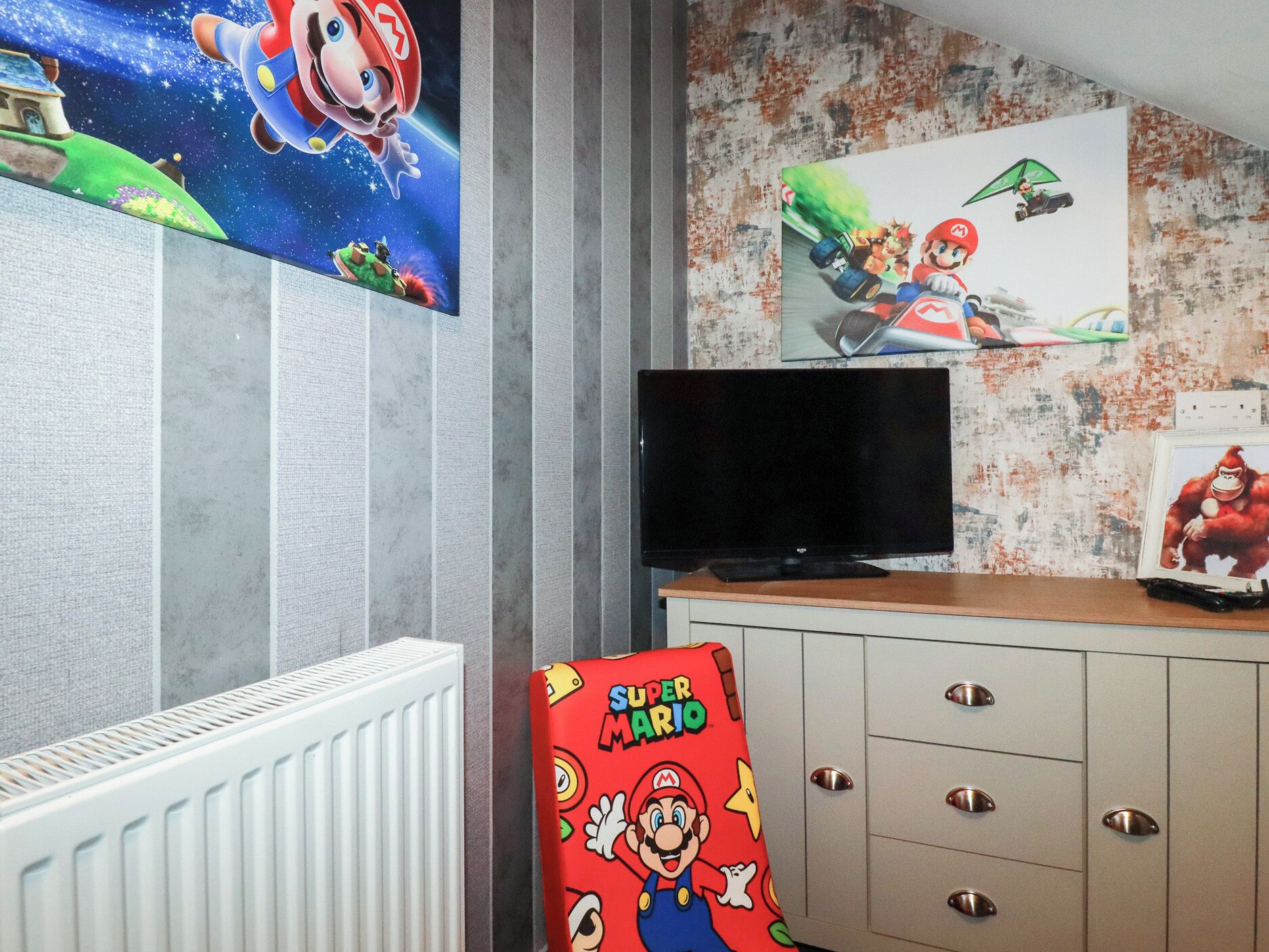 A room with a TV, Mario-themed artwork, and a cabinet.