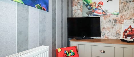 A room with a TV, Mario-themed artwork, and a cabinet.