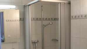 Kylpyhuone, jossa on lasiseinällä varustettu suihku, pesuallas ja wc.