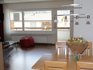 A modern living room with a wooden table, a red bean bag, and a bouquet of flowers. - Salute 206 # 4-bed apartment, Dusche, WC 4-Bettwohnung, Dusche, WC by Interhome (Leukerbad)
