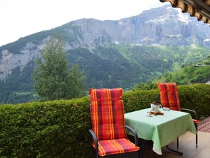 Een terras met twee stoelen en een tafel, met uitzicht op een bergachtig landschap.