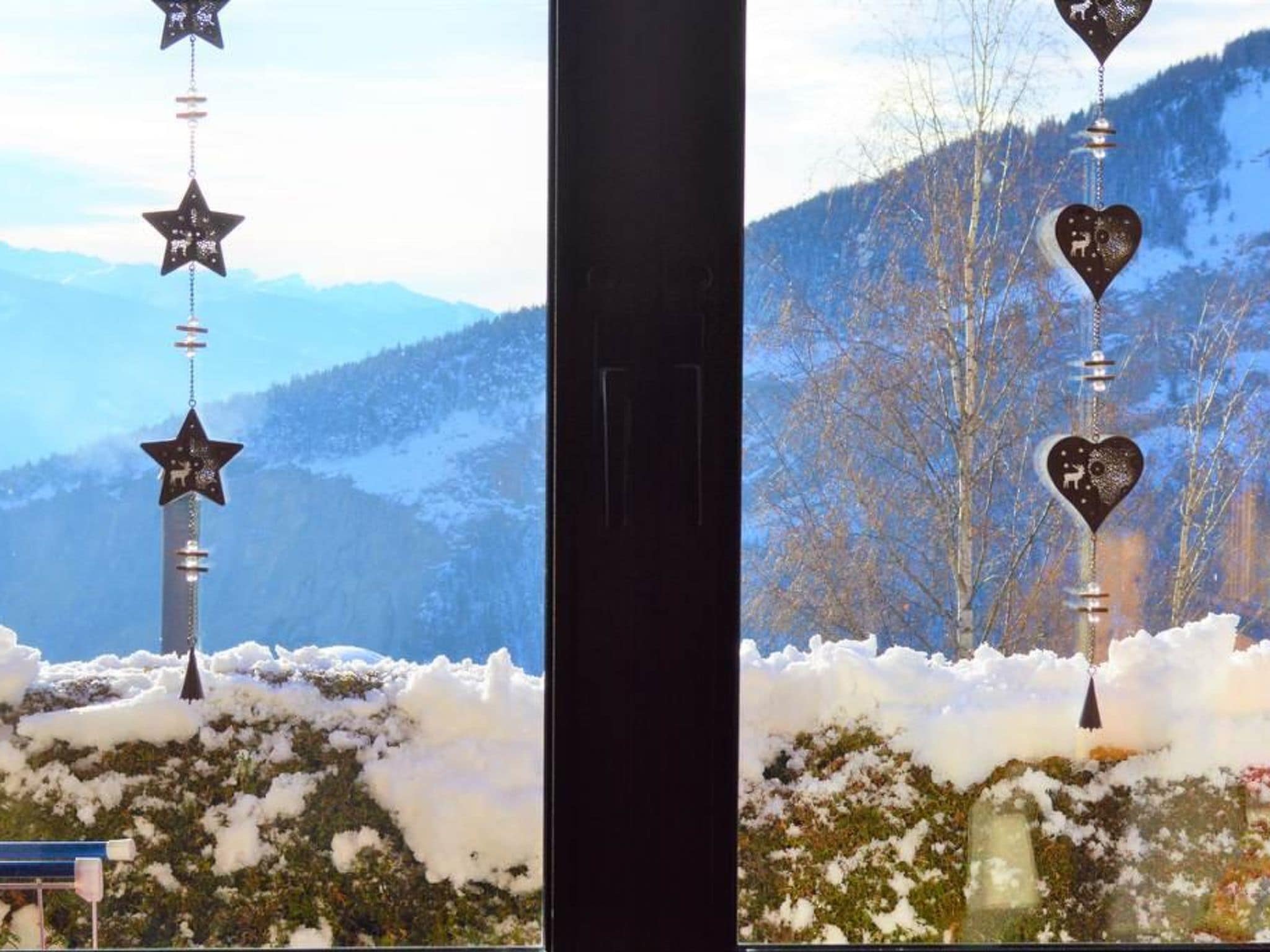 A window with a view of snow-covered hills and a clear sky.