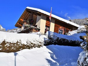 Eine Holzhütte mit schneebedecktem Dach, einer Flagge und einem Berg im Hintergrund.
