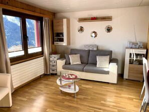 Ein gemütliches Wohnzimmer mit einer Couch, einem Glastisch und Holzboden.