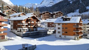 A snow-covered mountain resort with wooden buildings and balconies, surrounded by snow-covered trees and mountains. - Europe 16 # 4-bed apartment, Bad, WC 4-bed apartment, Bad, WC by Interhome (Leukerbad)