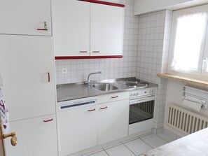 A kitchen with white cabinets, a stainless steel sink, a stove, and an oven. - Europe 16 # 4-bed apartment, Bad, WC 4-bed apartment, Bad, WC by Interhome (Leukerbad)