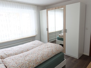 A bedroom with a bed, a wardrobe, a radiator, and a window with curtains. - Europe 16 # 4-bed apartment, Bad, WC 4-bed apartment, Bad, WC by Interhome (Leukerbad)