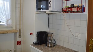 A compact kitchen with a microwave, a coffee maker, and a spice rack. - Europe 16 # 4-bed apartment, Bad, WC 4-bed apartment, Bad, WC by Interhome (Leukerbad)