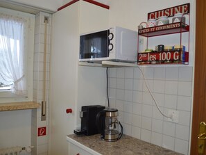 A compact kitchen with a microwave, a coffee maker, and a spice rack. - Europe 16 # 4-bed apartment, Bad, WC 4-bed apartment, Bad, WC by Interhome (Leukerbad)