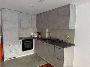 Una cocina moderna con gabinetes grises, horno empotrado, pileta y encimera con varios objetos.