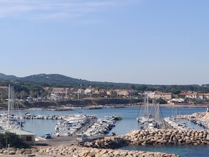 A marina with boats docked, surrounded by rocky terrain and buildings in the background. - Sea and Beach (Six-Fours-les-Plages)