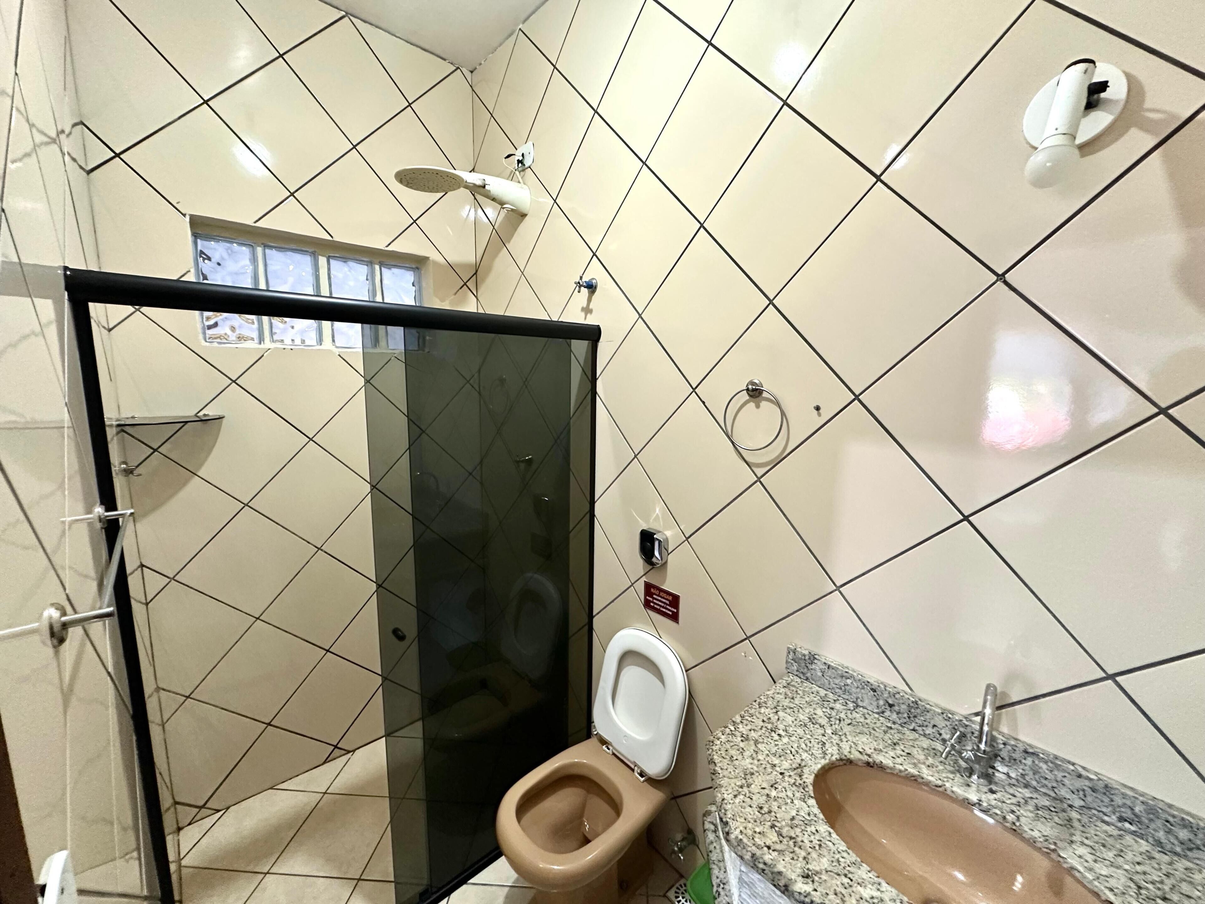 A bathroom with a glass-enclosed shower, a toilet, and a sink with a granite countertop.