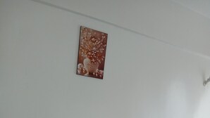 Quarto com sofá azul, cama branca e pintura pendurada na parede.