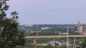 Une vue d’une ville avec un pont imposant, de la verdure et une grande sculpture au premier plan.
