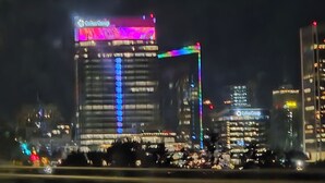 Un immeuble de grande hauteur doté d’une enseigne lumineuse, de nombreux étages et d’un dispositif lumineux vertical bien visible.