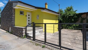 A yellow building with a stone facade, a white door, and a black metal gate. - Cozy house with jaccuzzi and barbecue (Dobreć)