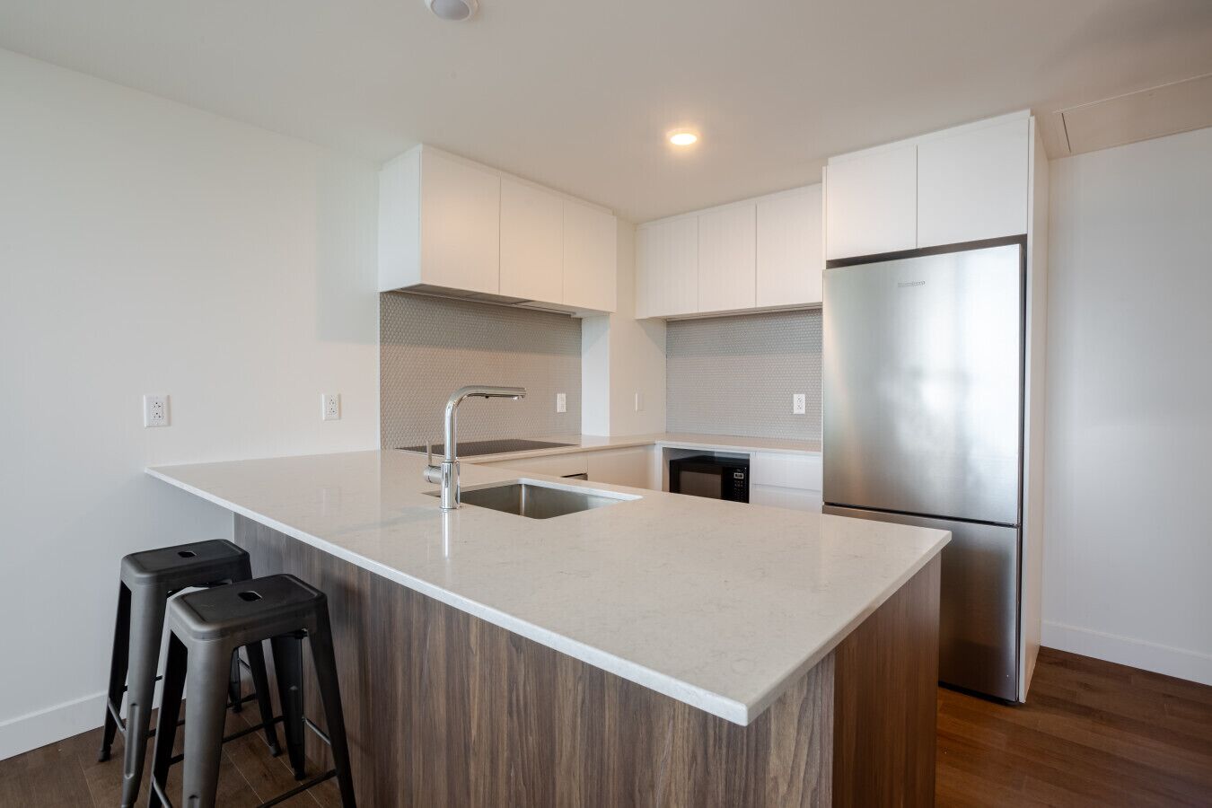 A modern kitchen with a large island, stainless steel appliances, and a minimalist design.