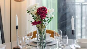 A dining table set with white plates, clear glasses, and a vase with flowers.