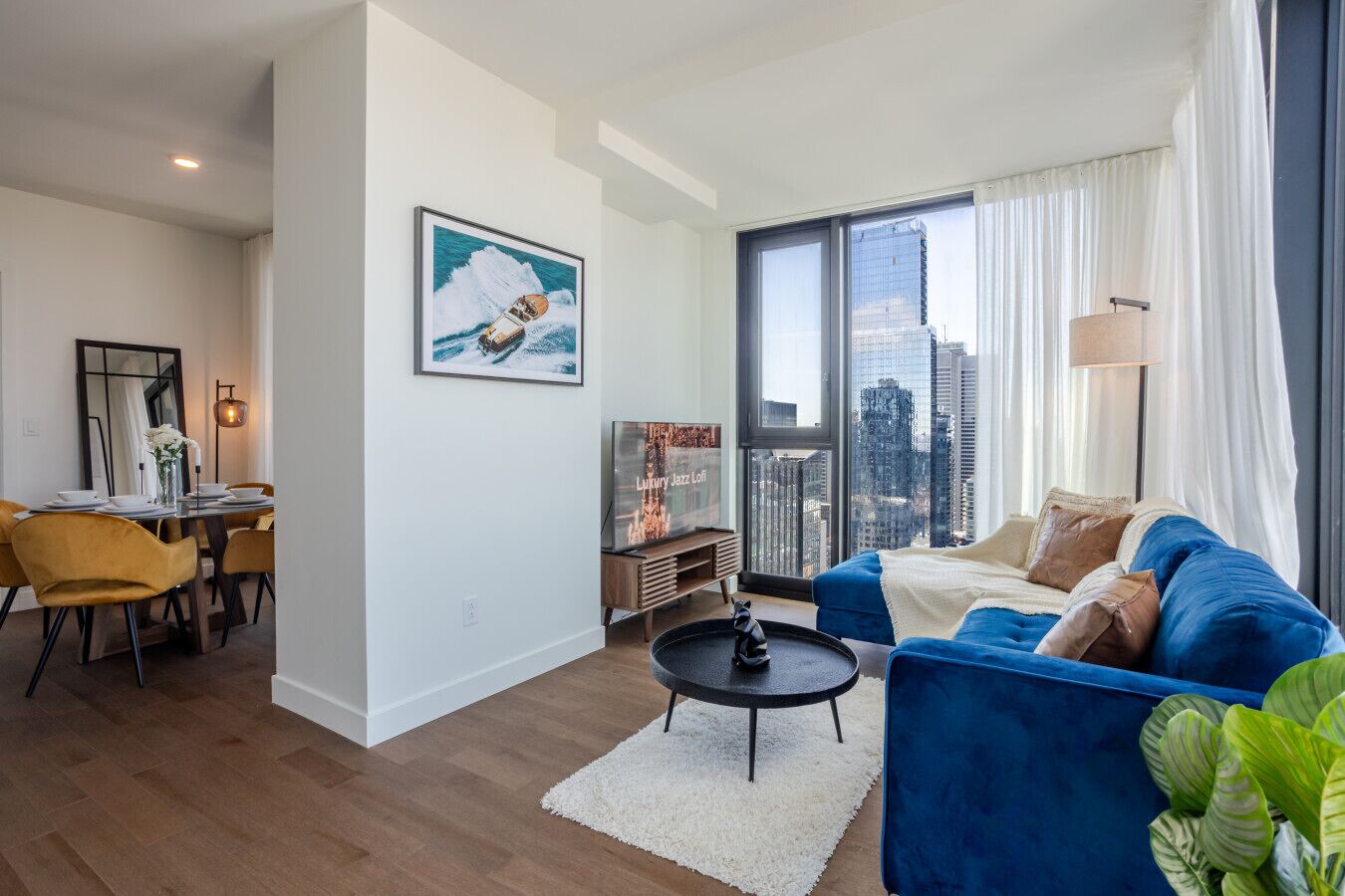 Un salon moderne comprenant un canapé, une table basse, un téléviseur et un coin repas avec des chaises et une table.