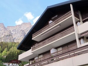 A multi-story building with a modern architectural style, featuring balconies and a prominent name sign. - Floralp 5 # 4-bed apartment, Bad, WC 4-Bettwohnung, Bad, WC by Interhome (Leukerbad)