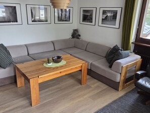 Un salon moderne avec une table basse en bois, un canapé gris et un chat.