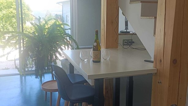A modern kitchen with a wooden island, bar stools, and pendant lights.