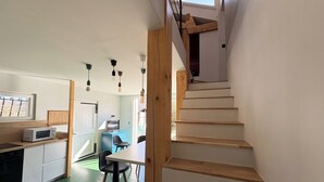 A modern kitchen with a microwave, wooden staircase, and a dining area with chairs.