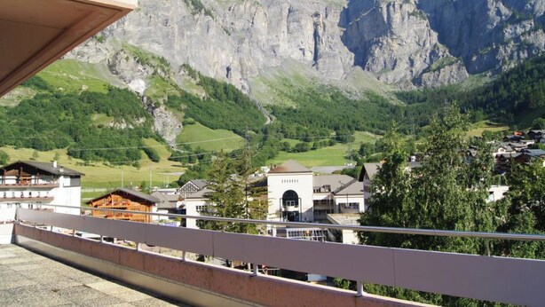 Une vue sur une montagne, avec un bâtiment au premier plan et une autre montagne en arrière-plan.
