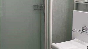 Un baño con cabina de ducha, lavabo y espejo.