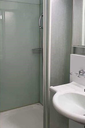 Ein Badezimmer mit Duschkabine, Waschbecken und Spiegel.