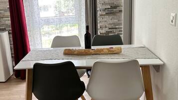Een eethoek met een tafel, stoelen en een fles wijn.