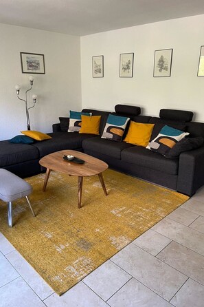 Ein modernes Wohnzimmer mit einer Eckcouch, einem Couchtisch und einem Teppich.