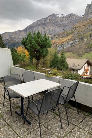 Eine Terrassenanlage im Freien mit Tisch und Stühlen, mit Blick auf eine gebirgige Landschaft.
