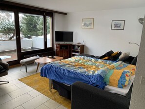 Ein Schlafzimmer mit Bett, Fernseher, Schreibtisch und Stuhl.