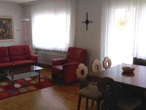 A living room with a red sofa, a red armchair, a glass coffee table, and a dining table with chairs. - Royal 50 # 4-bed apartment, Dusche, WC 4-Bettwohnung, Dusche, WC by Interhome (Leukerbad)