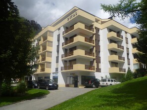 A multi-story hotel with balconies, a parking area, and a sign indicating 'Royal.' - Royal 50 # 4-bed apartment, Dusche, WC 4-Bettwohnung, Dusche, WC by Interhome (Leukerbad)
