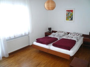 A double bed with two pillows, a bedside table, a lamp, and a painting on the wall. - Royal 50 # 4-bed apartment, Dusche, WC 4-Bettwohnung, Dusche, WC by Interhome (Leukerbad)