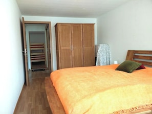 Ein Schlafzimmer mit einem Bett, einem Holzschrank und einer Tür zum Badezimmer.