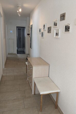 Ein Flur mit einer Bank, einem Holztisch und einem Heizkörper. An der Wand hängen gerahmte Bilder.