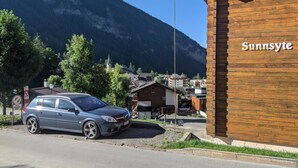 En byggnad med namnet ”Sunnyside” på fasaden, en parkerad bil och ett bergigt landskap i bakgrunden.