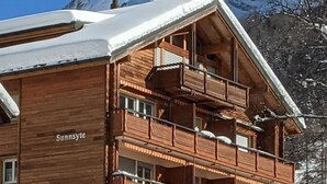 En flervåningsbyggnad i trä med balkonger, som kallas ”Sunnyside”, omgiven av snö och berg.