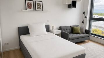 A modern bedroom with a bed, a sofa, a nightstand, and a window with a view.